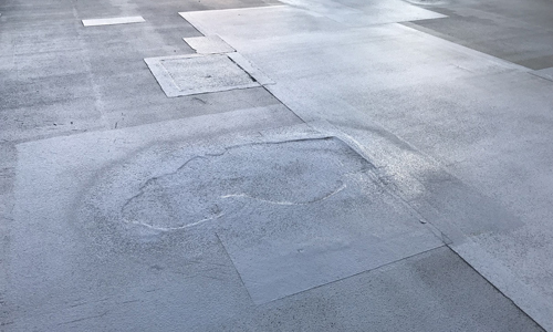 雨漏りが発生し、部分補修された工場や倉庫、店舗の屋上のイメージ